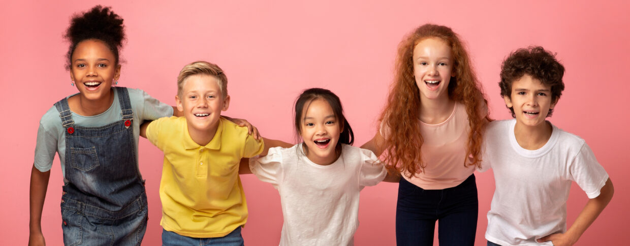 Portrait of multiethnic schoolkids smiling on pink background